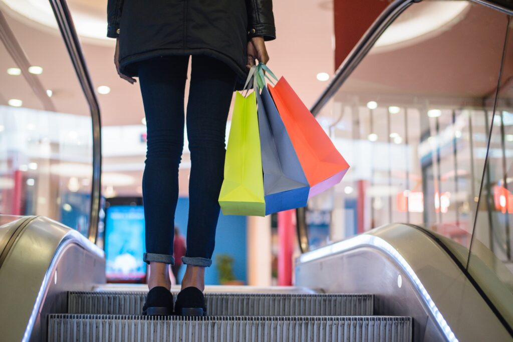 Woman legs with colourful shopping bags on the escalator in a shopping mall